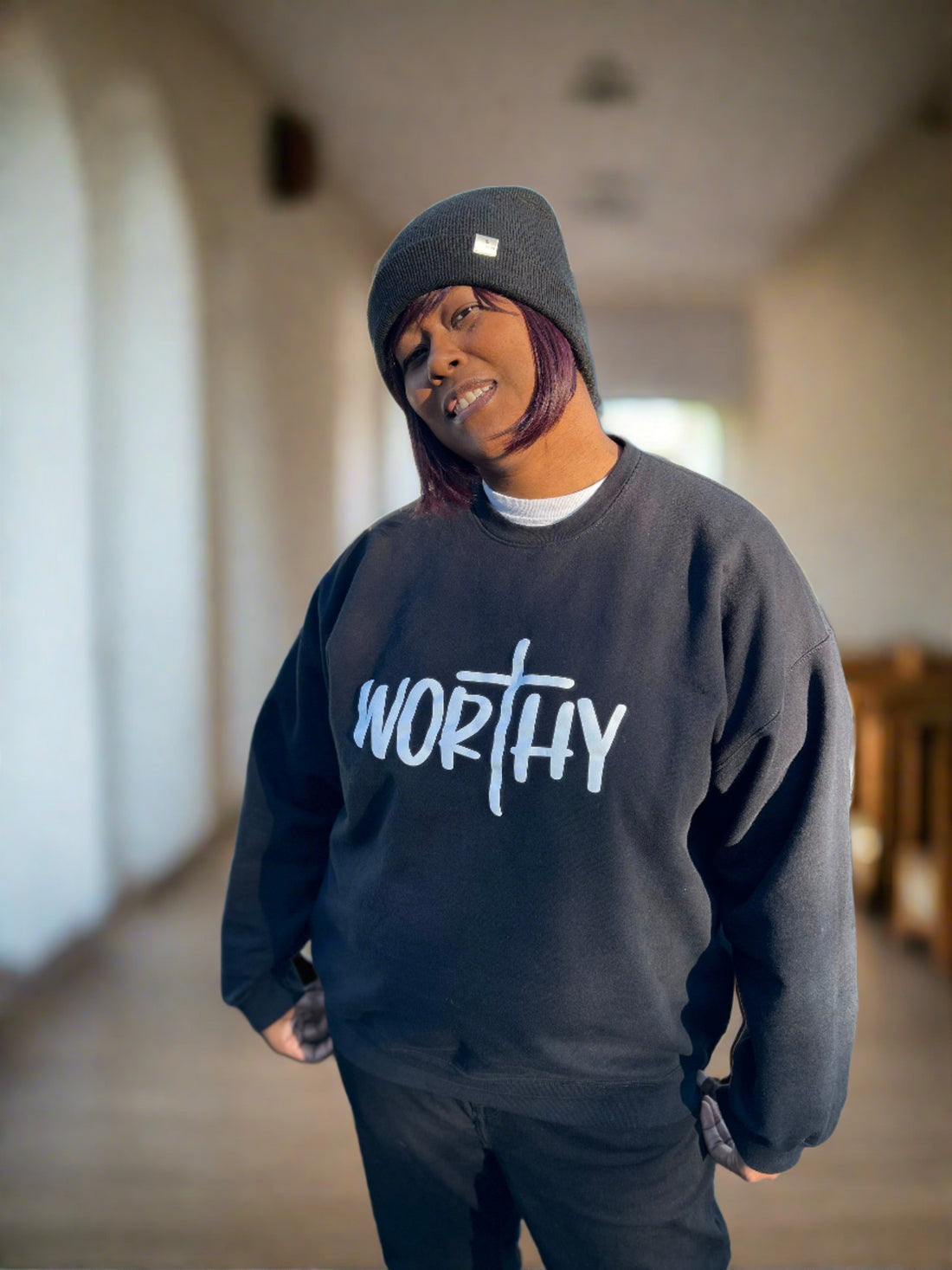 Black plus size woman wearing a black sweatshirt with the word, "Worthy" in white.